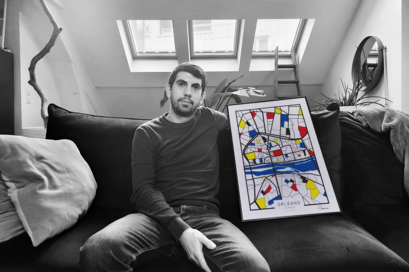Guillaume Deschamps assis chez lui, le plan d'Orléans de Plandrian encadré à côté de lui